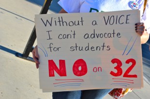 A demonstator holds up a sign advocating for No on 32 at the Palo Alto Caltrain station yesterday. Photo by Cathy Rong.