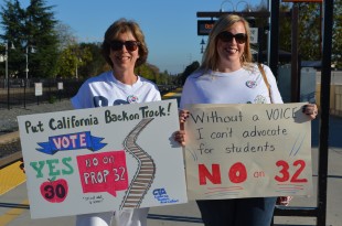Teachers Terri Baldwin and Kathy Patterson hold up their signs at a Caltrain demonstration to promote awareness about Prop 30 and 32 yesterday. Photo by Cathy Rong.