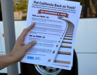 Demonstrators handed out flyers at the Caltrain station, for Yes on Prop 30 and 32. Photo by Cathy Rong.