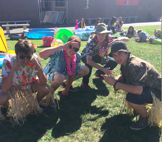 A group of junior boys crouch by their Hawaiian Island dressing themed decorations on the Quad. Photo by Chloe Fishman.