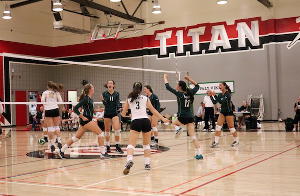 The Palo Alto High School girls' volleyball team celebrates after Senior middle blocker Claire Krugler gets a block against Mountain View High School. Photo by Victor Carlsson.