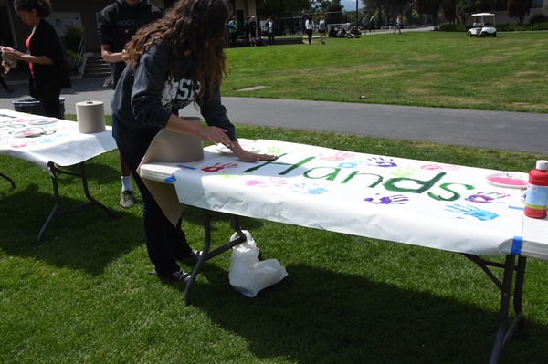 Senior ASB Treasurer Courtney Hall places a handprint onto the 'These Hands Don't Harm' poster set up in the Quad during lunch on Wednesday for Sexual Assault Awareness Day during Not In Our Schools Week 2015. This year, the focus will be on the positive aspects instead. Photo by Liana Pickrell.