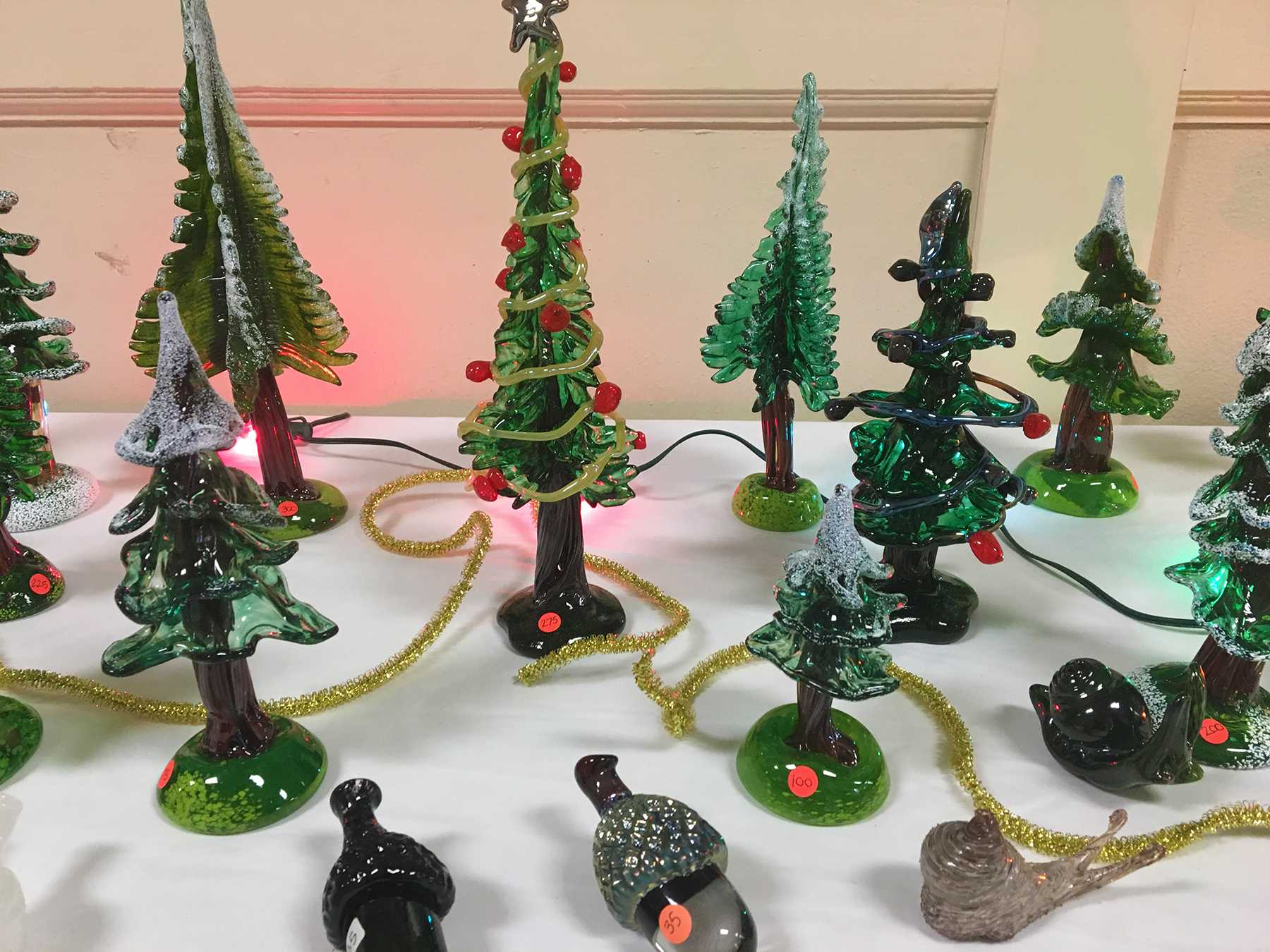 Christmas trees are displayed next to acorns and a whimsical slug sculpture. The glass acorns were first introduced at this year's Fall Fiery Arts Sale, and have continued to be included in the winter sale. Photo: Sophia Muys