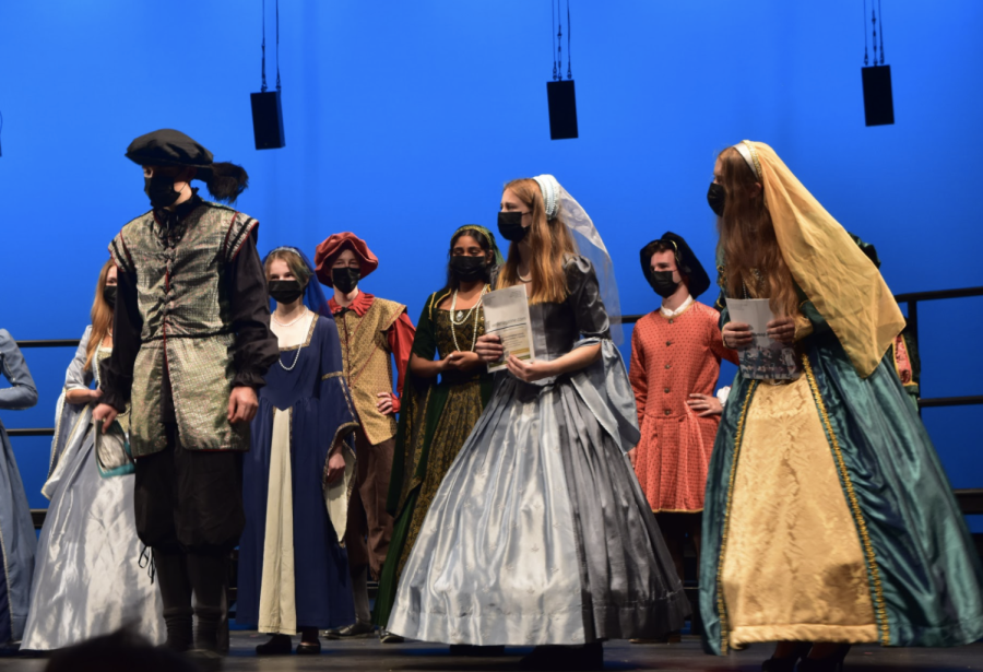 Palo Alto High School’s Madrigals Choir performs a skit during the fall concert last Friday. Wearing an authentic madrigals dress, Senior Cate Dyer walks to the front of the stage holding a magazine as she preludes the next song they will perform. 