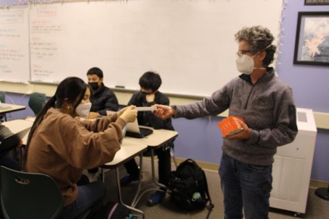 A substitute teacher distributes at-home COVID-19 tests to students in an AP Language class. 