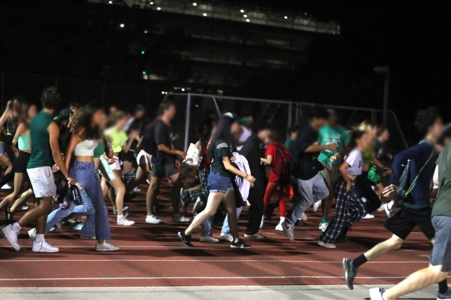 Students from Palo Alto High School rush across the track and return to their side of the field after raiding the Gunn High School bleachers. Some students, including junior Ava Iribarren, are upset with the proposed scale backs to Spirit Week that Principal Brent Kline may officially announce tomorrow, including the potential cancellation of the Homecoming Dance and reduced number of rallies. “I don’t think it is fair to punish the entire student body for a couple of people’s decisions which led to everyone else following,” Iribarren said. “I wasn’t there, and a lot of my friends weren’t there, and I don’t think it is fair to punish everyone and even just won’t be fair to punish the people who were at the game.” (Photo: Annelise Balentine)