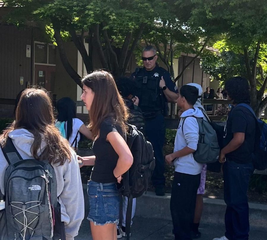 A police officer talks with students as they regroup during brunch today near the Palo Alto High School Library. Officers were called onto campus to investigate an anonymous shooter threat taped to a social studies classroom door. According to history teacher Jack Bungarden, the administration handled the response to the threat in an adequate manner. “The leadership of the school did an excellent job of responding,” Bungarden said. “There were problems with communication and some clarity and some confusion. But even if we were well trained and well prepared, and this is part of the scenario that we had practiced, theres still going to be an element of that. Perfection is hard to achieve.” (Photo: Leena Hussein)