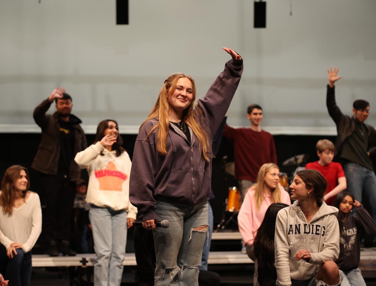 Senior Rori Escudero waves towards the crowd during rehearsal in preparation for the Palo Alto High School Choirs Pops Concert. Paly Choirs will perform their annual concert to the theme of Make-up/Break-up” at 7 p.m. today and tomorrow in the Performing Arts Center. Escudero said she is excited to hear her classmates sing. “I am looking forward to hearing everyones solos, especially the underclassmen and people who havent had solos before,” Escudero said. “Its cool getting to hear people have their big moment for the first time on stage.” (Photo: Celina Lee)