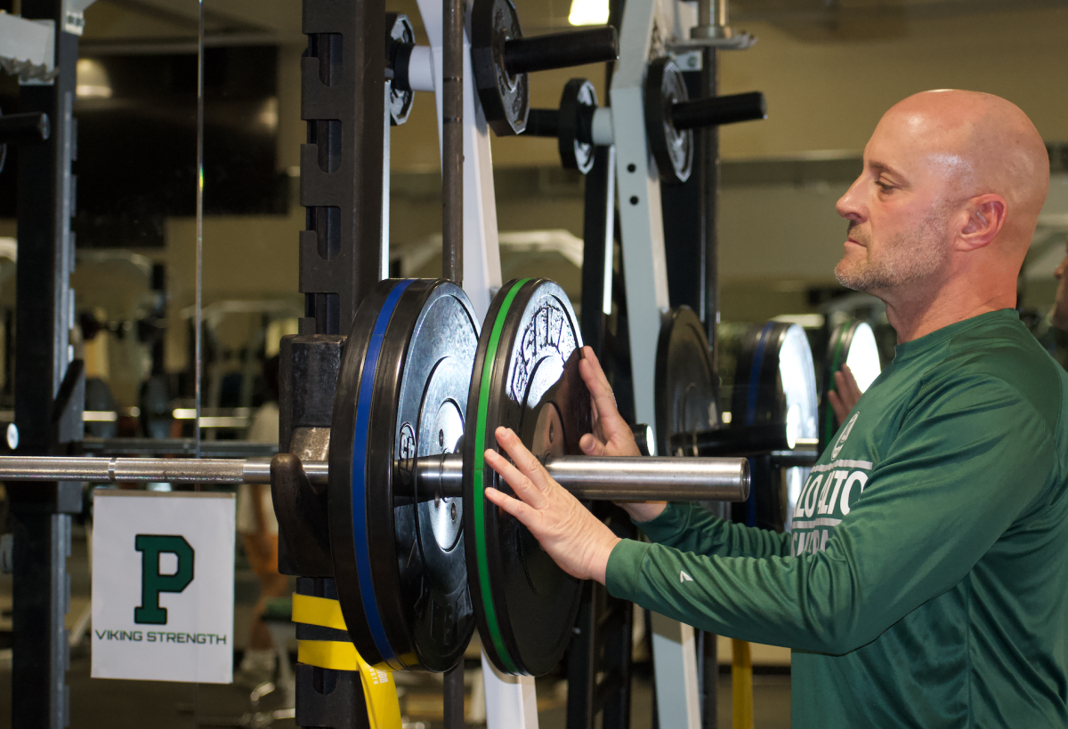 Strength and conditioning coach Anthony Thomas sets up the weight room in preparation for another session with the Paly Football Team. According to Athletic Instructional Leader Peter Diepenbrock, Palo Alto High School is late to the game in implementing a conditioning program. Most, if not all of the top athletic teams in the area have had a strength and conditioning program for many, many years, said Diepenbrock. We are very, very late.(Photo: Joy Tan)

