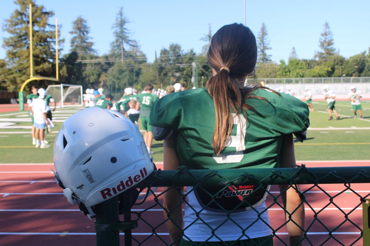 Kicker Lara Saslow, a junior on palo Alto High School boys' football team, looks towards her team, waiting to jump into a drill. Saslow needs to not only juggle her multiple classes, but at the same time, dedicate time and energy into her two sports -- boys' football and girls' flag football. "It's pretty stressful balancing flag, tackle, and school, "A big part of it is being on varsity and having to go to morning practice."