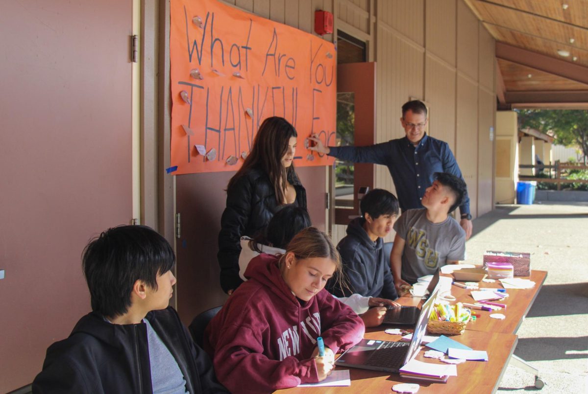 Associated Student Body members watch as history teacher Stephen Foug places a thankfulness note onto a poster in front of the ASB classroom during lunch on Monda. Sophomore Tiam Maurstad said that he appreciates ASB's efforts for Thankfulness Week. "ASB's work brings a good spirit to Paly and brings people at school together." Maurstad said. 