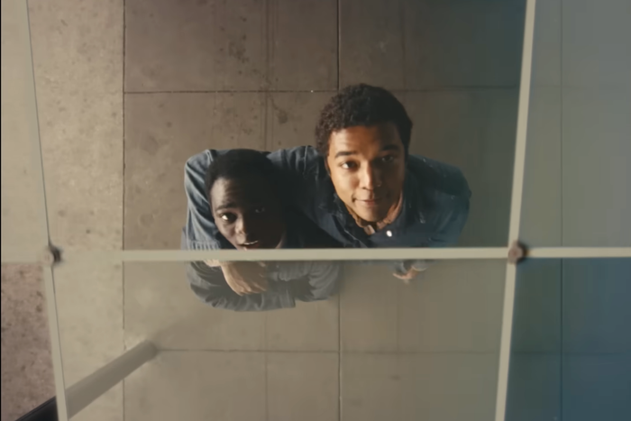 Elwood Curtis (Ethan Herisse), left, and Turner (Brandon Wilson), right, walk back to Nickel Academy after working in the city, pausing beneath a glass ceiling as they look up at a construction site in the historical drama "Nickel Boys," which received two Academy Award nominations. Directed by RaMell Ross, Colson Whitehead’s Pulitzer Prize-winning novel comes to life, exposing the brutal realities of Nickel Academy and the resilience of those trapped within it.