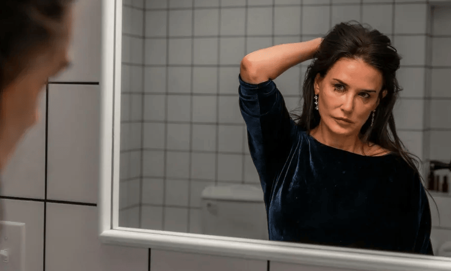 Elizabeth Sparkle (Demi Moore) stares into the mirror, frustrated as she examines her aging face in "The Substance."