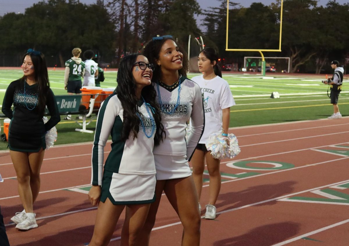 Senior cheerleaders Cailey Quita and Lasaides Voorhees smile at the stands.