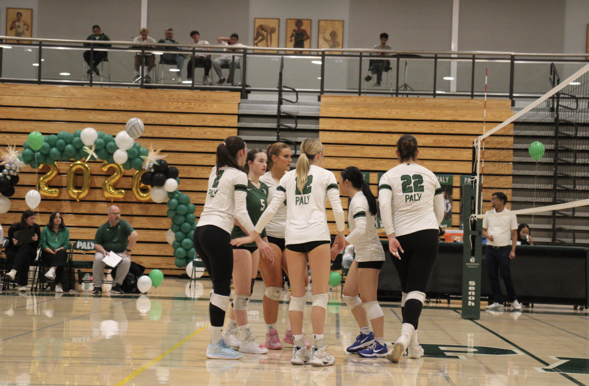 The Palo Alto Vikings girls' volleyball team huddles after scoring a point against the Milpitas Trojans on Thursday night, at Palo Alto High School. According to Viking head coach Chris Crader, the Vikings couldn't get any momentum once they lost the first set. "When you get down, you don't have to be amazing at the moment. You just have to find a way to just chip away, and get a little bit better," Crader said. "But we couldn't find that, and I couldn't find the right lineup to kind of generate any momentum."