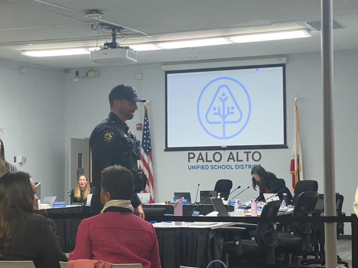 A police officer walks across the room during a break in the board meeting this Tuesday. According to board president Shounak Dharap, an officer was stationed due to online threats made to the district. “The district was made aware of statements by an individual that contained language that I believe posed a potential threat to the safety of the people in this room,” Dharap said. “I take those statements incredibly seriously.”