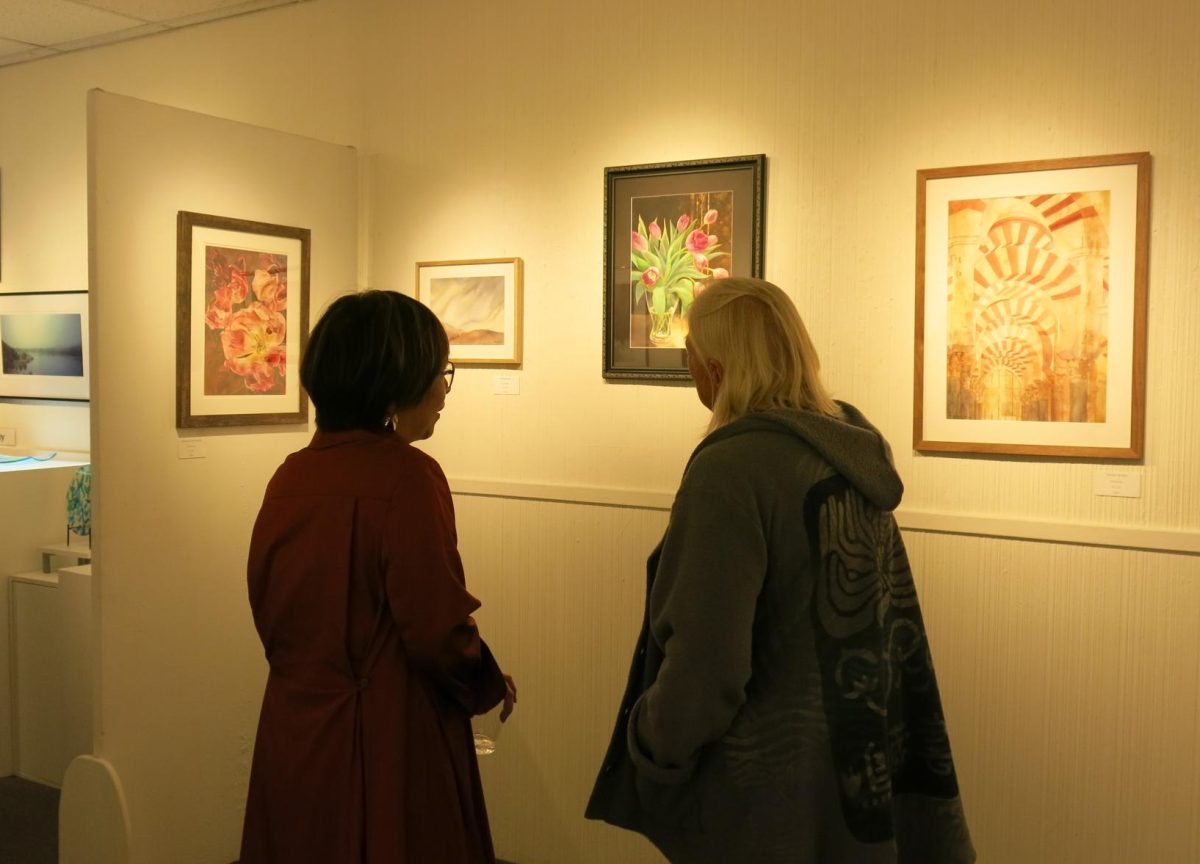 Artist Mami Weber discusses her artwork with a viewer at Gallery 9 in Los Altos during her exhibition’s opening celebration on Friday. Weber said she paints in watercolor because of the medium's capacity for organic movement. "I allow the paint to move freely, accepting what cannot be fully controlled," Weber said. "I invite viewers to slow down, sense what remains, and reflect on moments that once felt ordinary, yet continue to resonate."