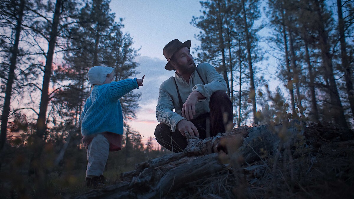 Robert Grainier (Joel Edgerton) shares a quiet moment with his daughter Kate (Olive Impellizzeri Steverding) in "Train Dreams" (2025), a reflective drama that follows a railroad laborer navigating life and loss in the early 20th-century American West.