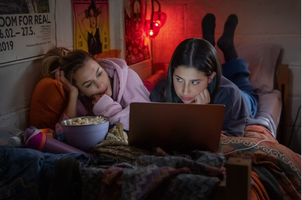 Devon (Sadie Sandler) and Celeste (Chloe East) lie on their bed in their dorm watching a movie, in the movie "Roommates" directed by Chandler Levack.