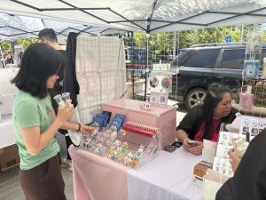 Rosalind Tsai, a junior from Mountain View High School, checks out custom stickers Sunday afternoon at a booth during the BTS Stanford Vendor Market. According to Tsai, BTS has always provided a refuge throughout her years as a fan. “I’ve been an ARMY since I was seven or eight, and throughout all these years, BTS has always been a great comfort,” Tsai said. “All their content, like their variety shows and random livestreams, always create a space for stress relief, joy and laughter. … To me, being an Army means being heard and healed.” 
