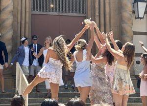 In a senior prank, wedding bridesmaids reach for bride senior Delilah Kaplinsky's bouquet in front of the Haymarket theatre at Palo Alto High School during Lunch. According to senior Dylan Liao, the atmosphere was what made the prank memorable. “My favorite part was just the overall vibe,” Liao said. “Everything was pretty fun, and I liked the music. I also liked the ceremony, how everyone was there, and the energy was great.”