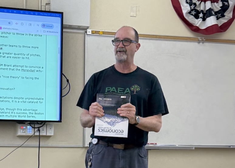 Economics teacher Eric Bloom encourages students to return their textbooks for the end of the year. According to Bloom, students might have recognized his unique fashion choices including vibrant shoes and belt buckles. Bloom said his attire choices actually linked to his lessons. "I have a lot of shoes, I have a lot of belt buckles and wear them purpose because of its educational value," Bloom said. "Especially in the earlier part of my career when we would talk about product differentiation, I had an assignment where students go home and count how many different kinds of shoes [they have]."