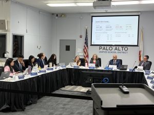 Charen Yu (left), the Palo Alto Unified School District chief business officer, presents the updated 2026-2027 budget during Tuesday's board meeting. According to Yu, expenditure changes are the primary reason for the deficit. “[Compared to the adopted budget], certificated salaries are up $18.8 million (which translates to 13.4%), classified salaries are up $11 million (or 17%), benefits are up $5.6 million and all other objects are down $2.9 million,” Yu said. “These are settled agreements with our bargaining partners. They are contractual obligations and they are the primary driver of the change.”